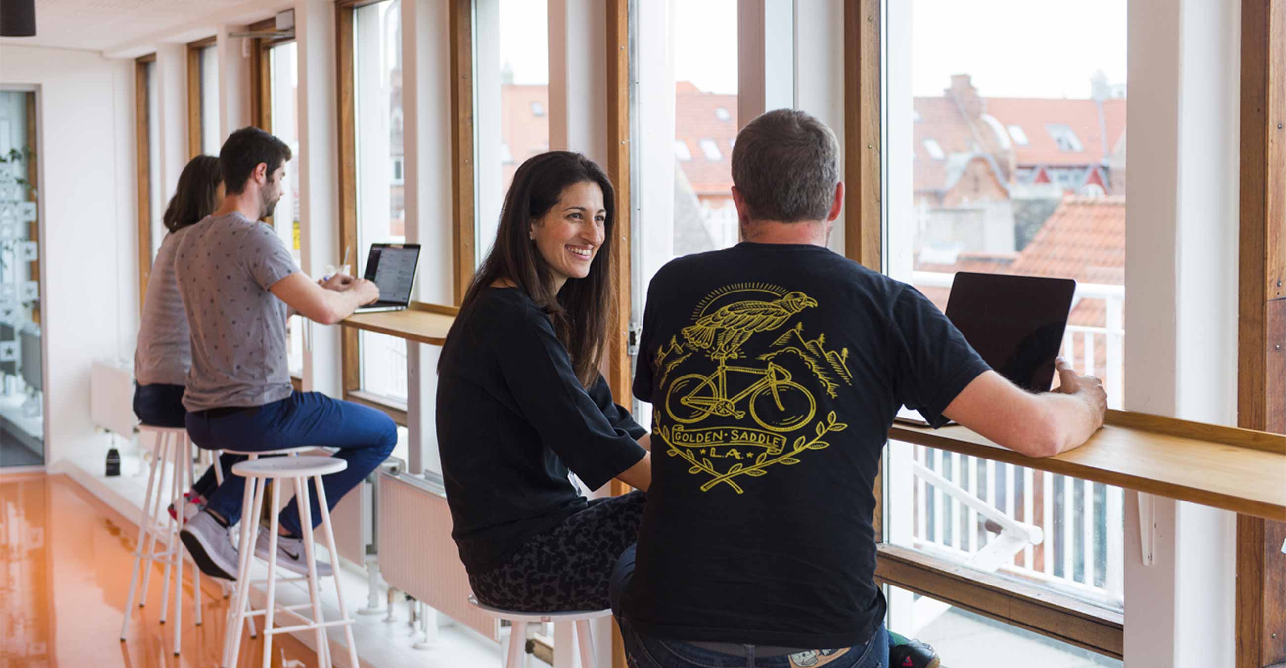 A photograph of smiling Trustpilot employees collaborating in sunshine.