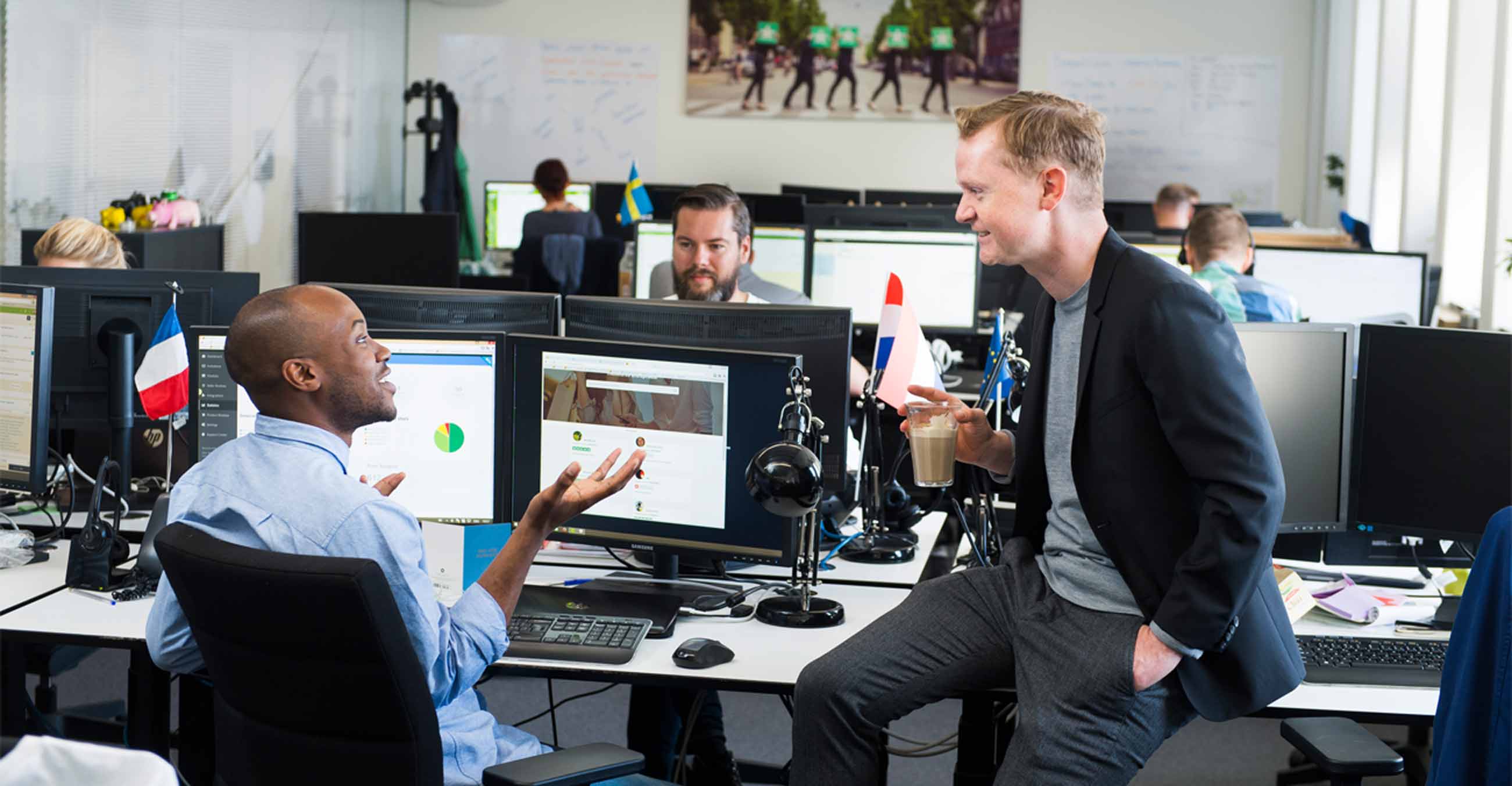 A photograph of Trustpilot CEO, Peter Holten Mühlmann, engaged in friendly conversation with a Trustpilot employee in Trustpilot's office.
