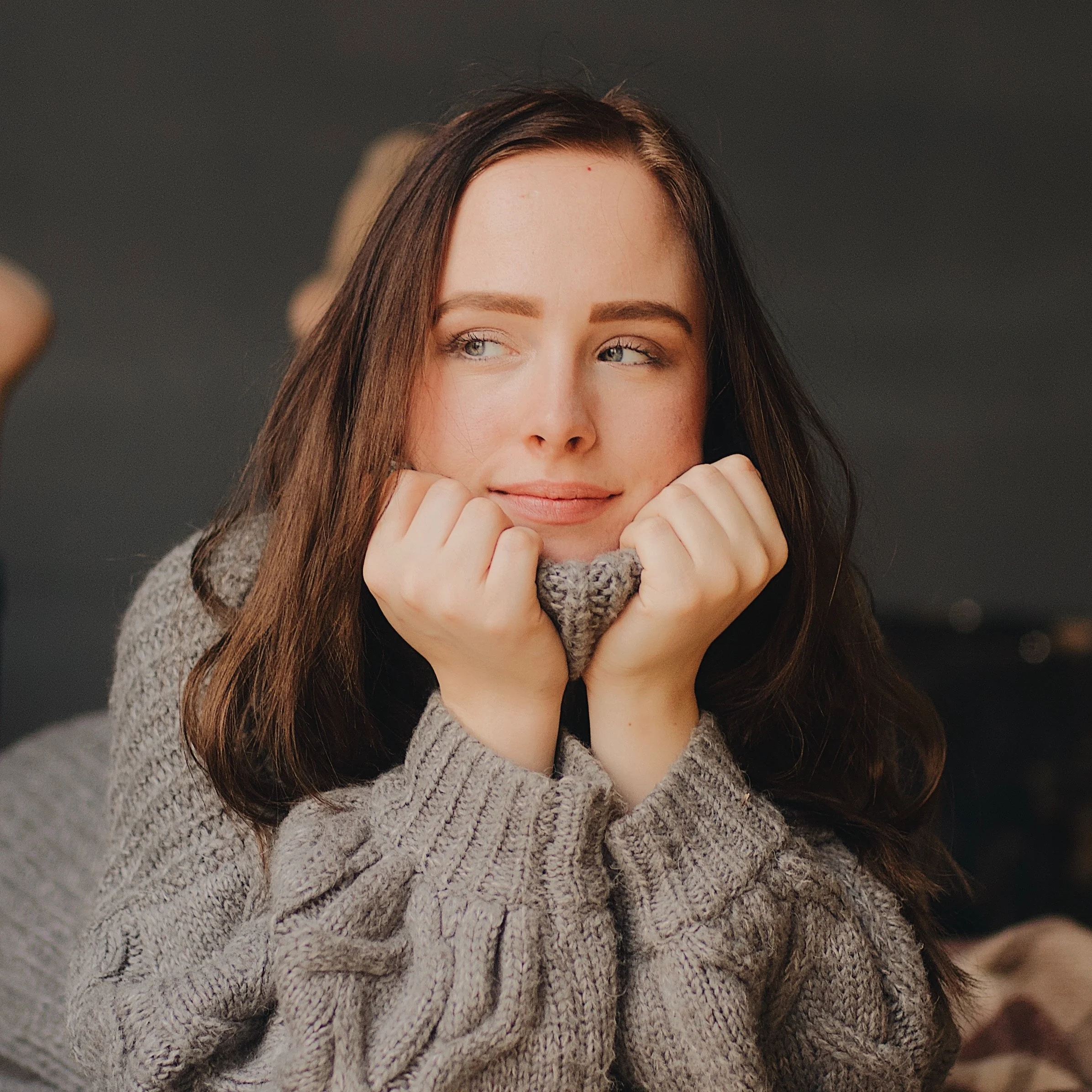 Woman with brown hair in big grey sweater